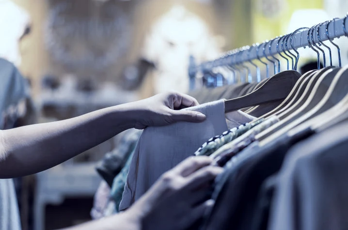 Shopper browsing garments on a clothing rail